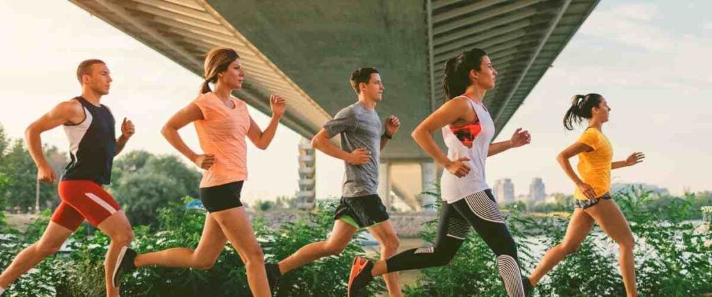 Group of runners outside and under a city bridge. 