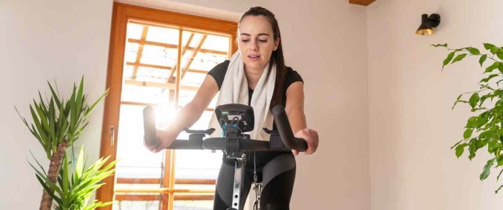 A woman on her exercise bike in her living room on a ride.