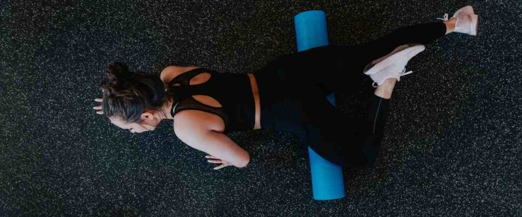 Women at gym foam rolling her guads.