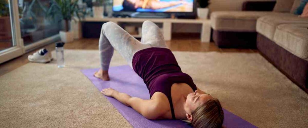 Woman doing the bridge stretch in her living room on a yoga mat 