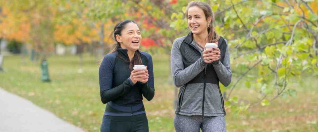 2 runners drinking coffee before their run in a park. 