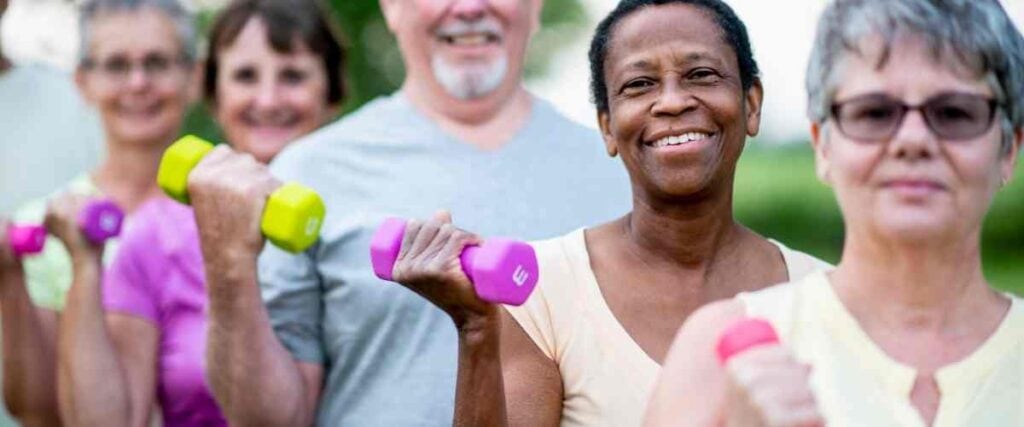 A group of older adults holding weight smiling into the camera.