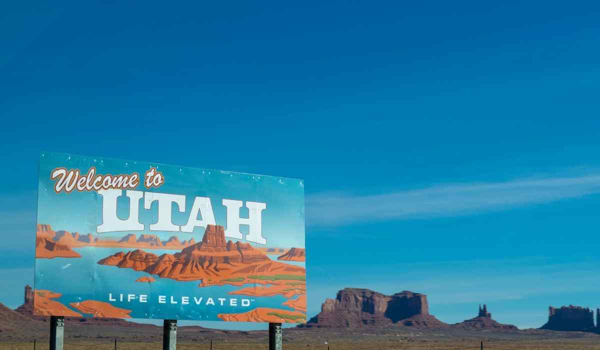 Beautiful blue welcome sign to Utah against the blue sky and mountains backdrop and the sign reads "Welcome to Utah - Life Elevated"