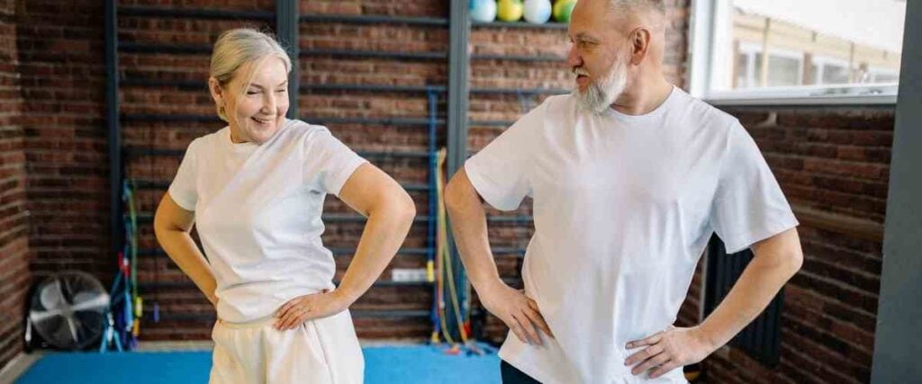 An older couple swaying their hips to warm up before a workout. 