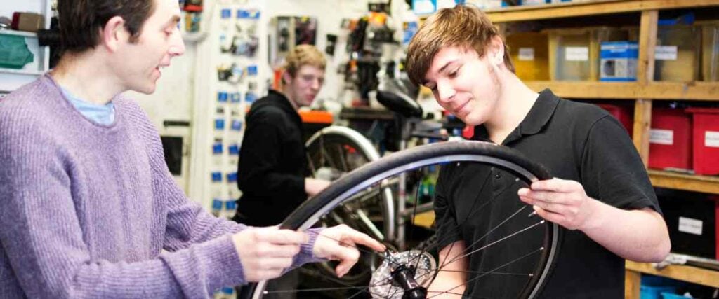 A man at a bike shop looking at his wheel. 