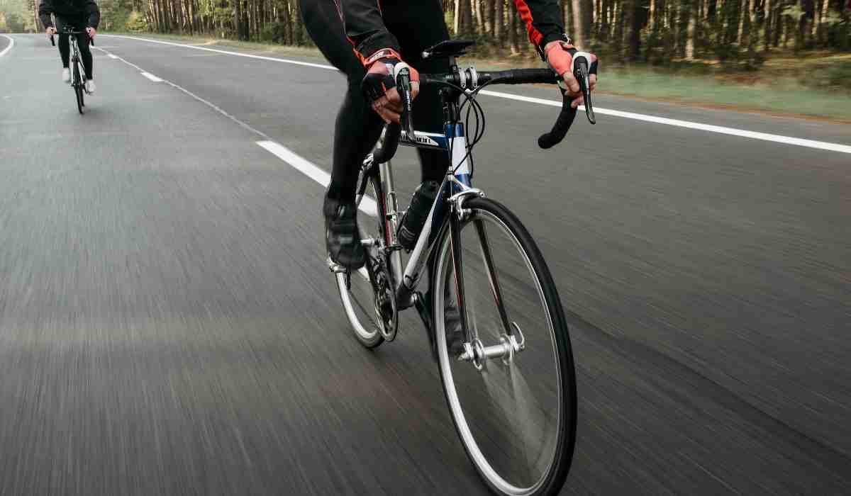 A cyclists on the road with a closeup of her handlebars and front of the bike.