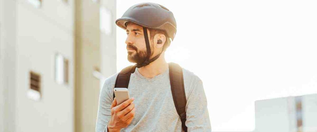 A male cyclists with wireless headphones on. 