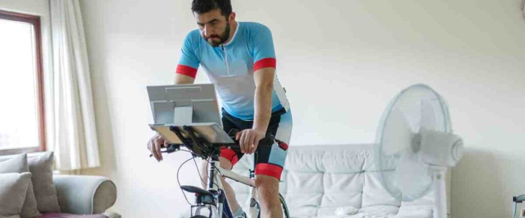 A male cyclists on his indoor trainer watching his computer from his mount on bike