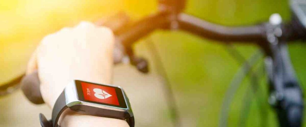 A cyclist checking his smart watch to look at his heart rate.