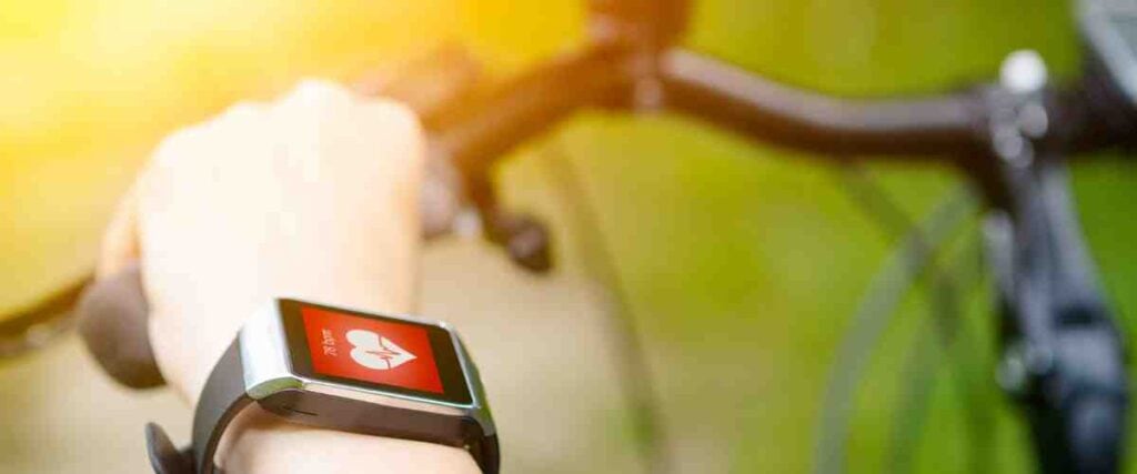 A cyclist checking his smart watch to look at his heart rate. 