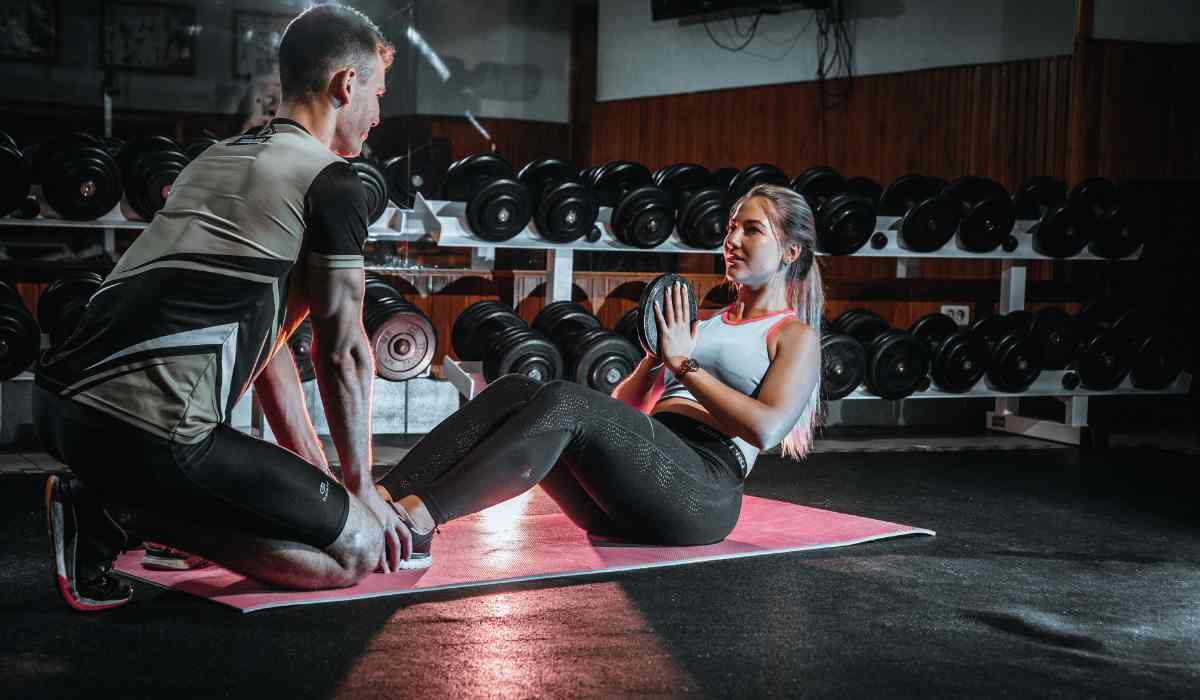 A couple working out, while woman is doing a crunch and the male is holding her feet.