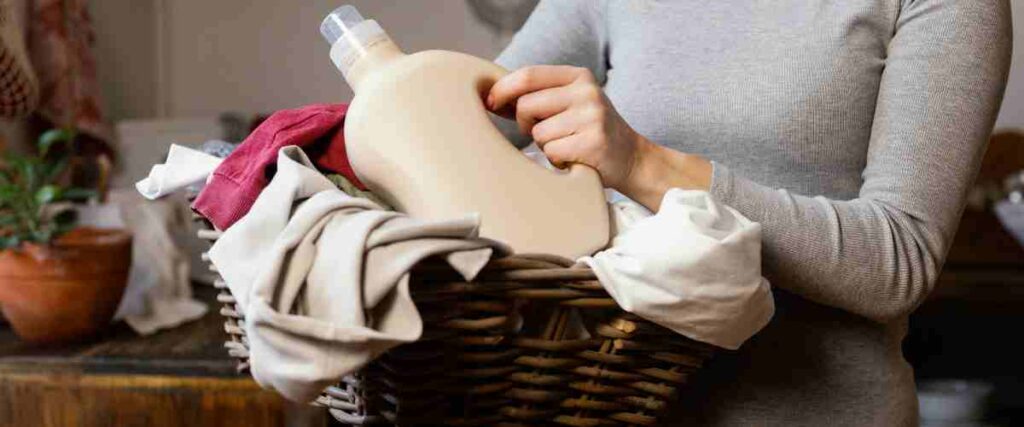 Woman holding laundry basket and laundry detergent bottle.