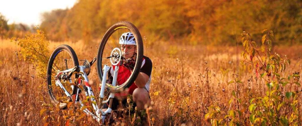 Cyclists fixing flat tire in field. 