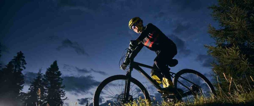 Cyclists in the dark going down hill.