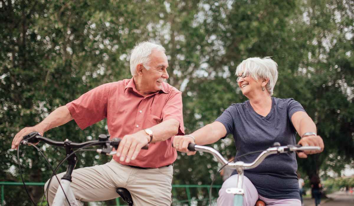 An older couple looking at each other smiling while on a bike. 