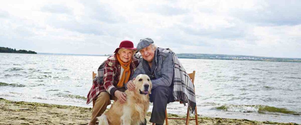 Older couple on beach with their dog. 