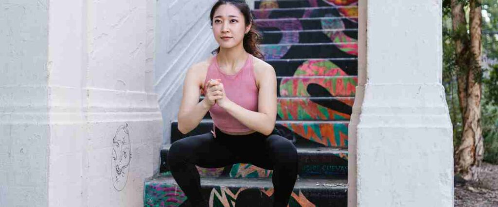 Woman doing lunges at bottom of stairs. 