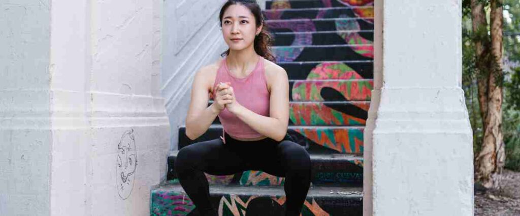 Woman doing lunges at bottom of stairs.