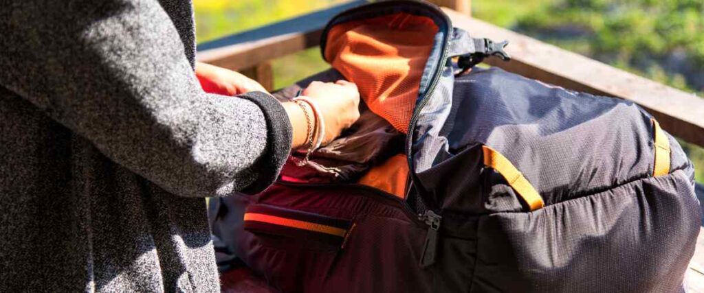 A woman opening up her backpack on porch.