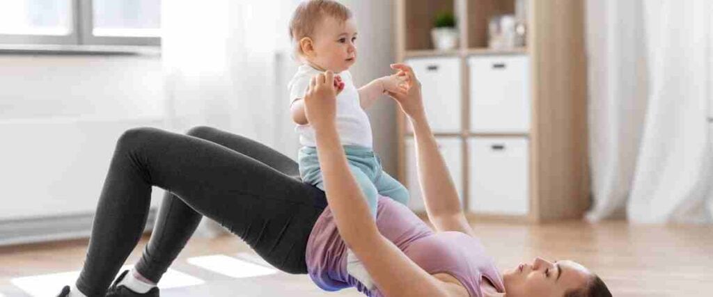 Woman doing bridge pose with her child.