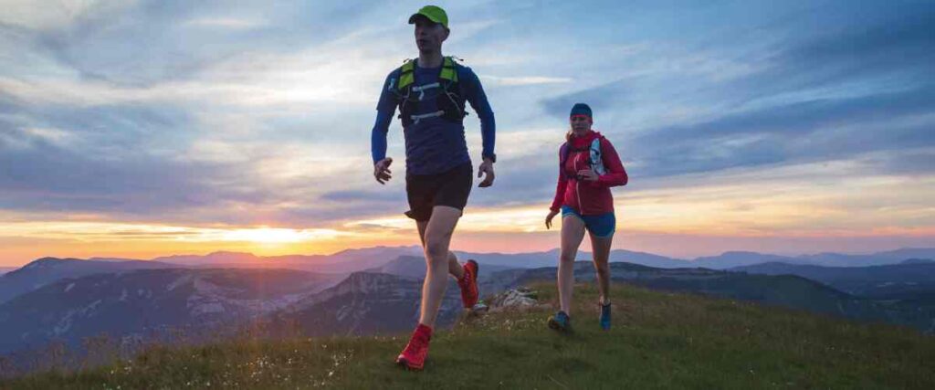 Two runners on top of a mountain. 
