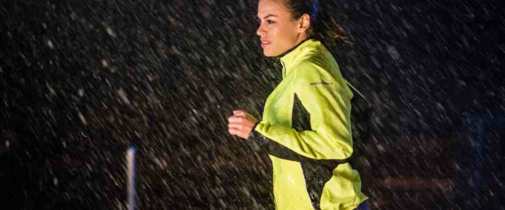 Woman running in the dark while it rains.
