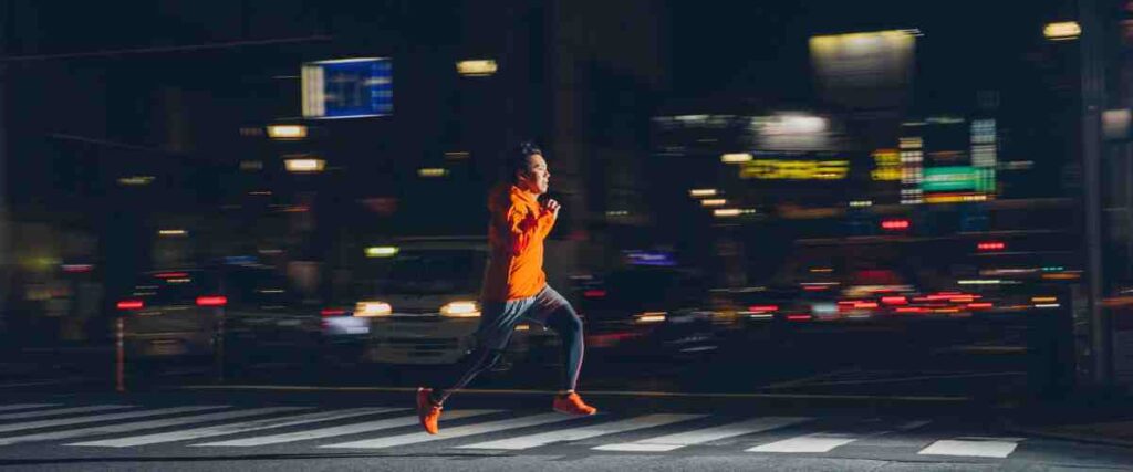 Man running at night wearing bright reflective clothes.
