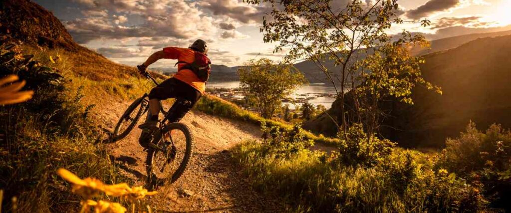 Mountain biker taking a steep turn down the hill at sunset. 