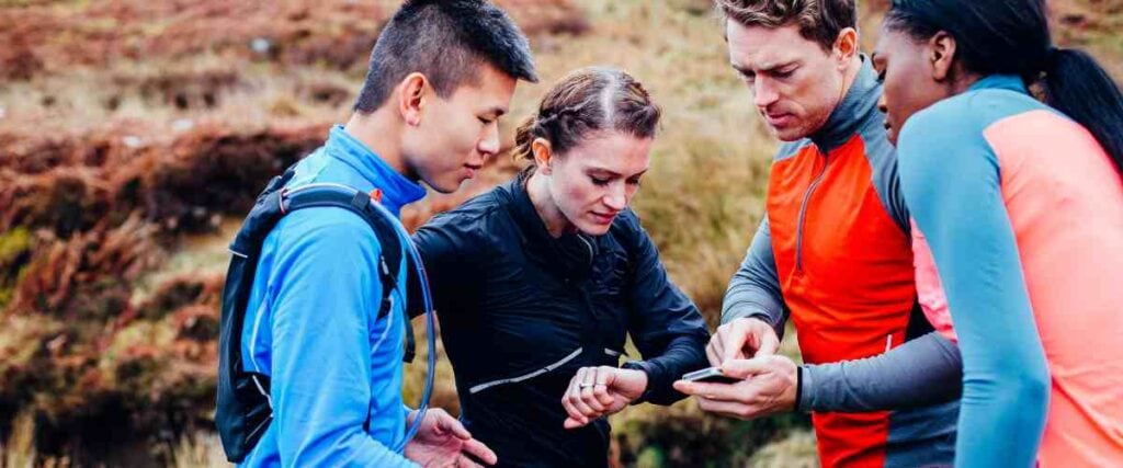 A group of runners looking at their watches and phones. 