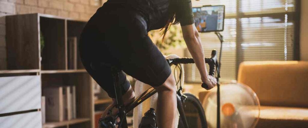 Female cyclists on her indoor trainer in her living room. 