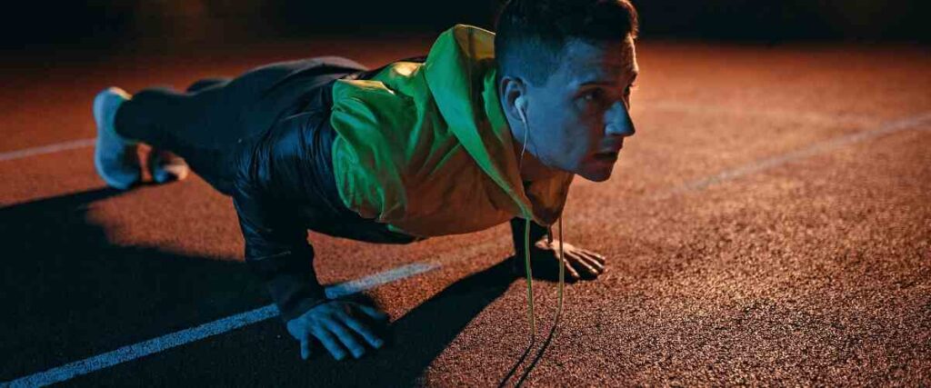 Man doing a stretch late at night on track field 