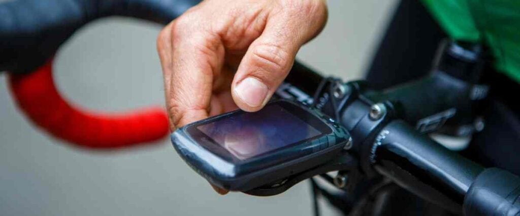 A cyclists touching his bike power meter. 