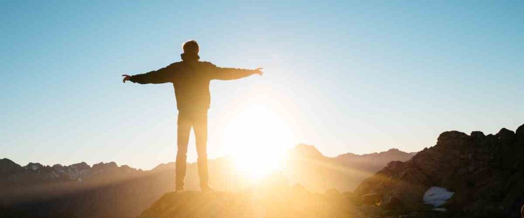 Man on a mountain taking in the sunlight. 