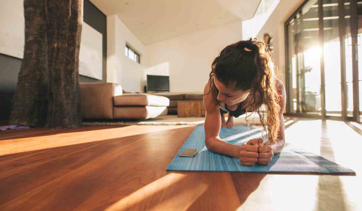 Woman doing a plank on a yoga mat in her living room.