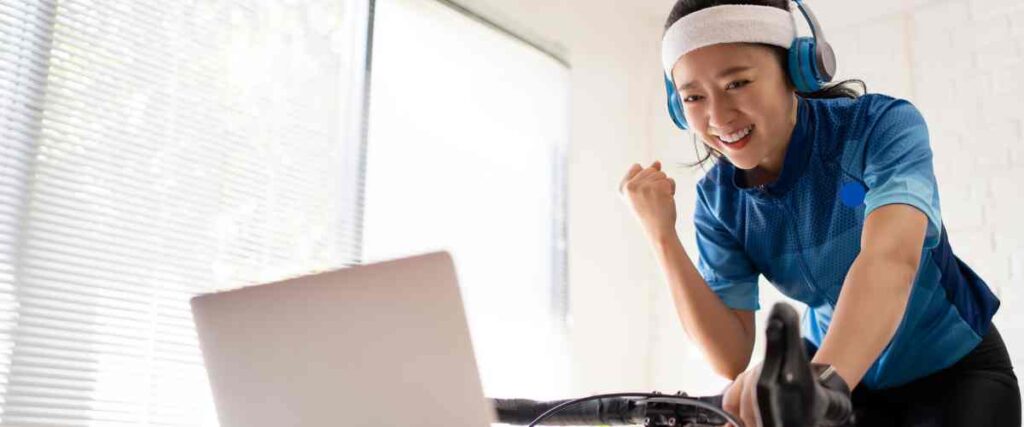 Female cyclists using wireless headphones while working out and looking at her computer. 