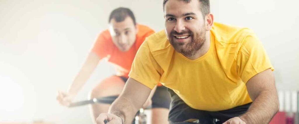 Two men in a cycling class looking forward.
