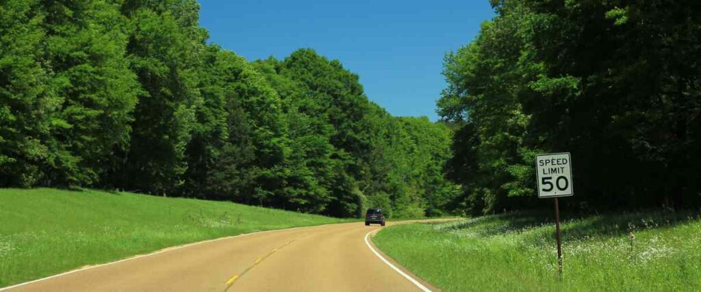 Natchez Trace Parkway from behind a truck taking a turn in the middle of the day in the summer. 

