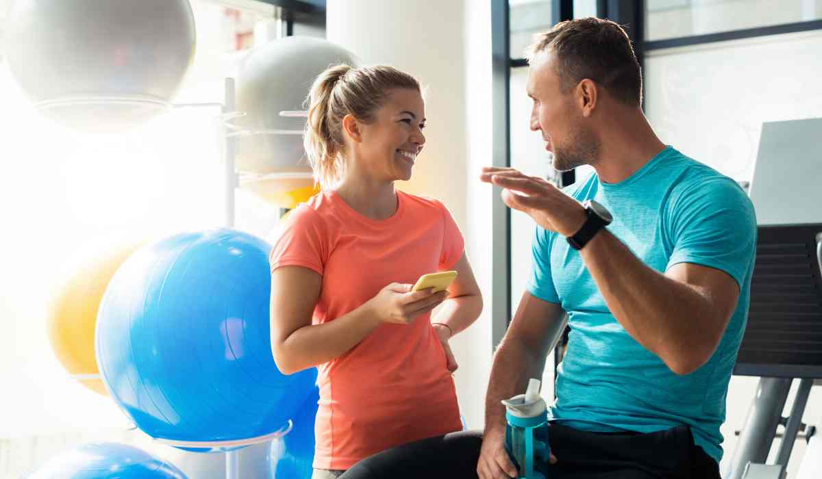 Two people at a gym smiling at each other while talking!