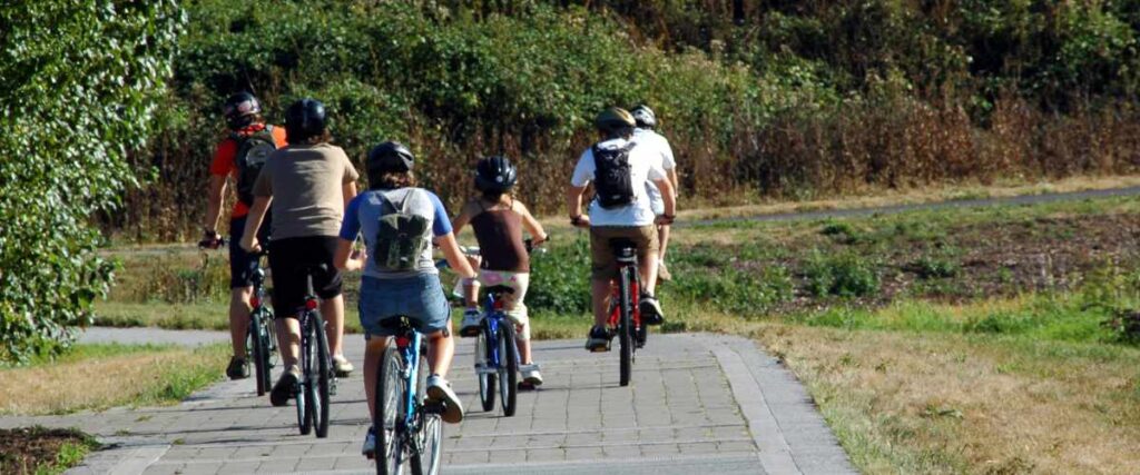 A family on a bike path going around a corner together. 