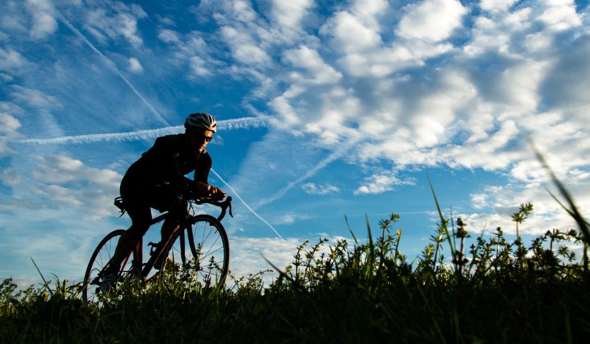 A male cyclist on a country trail with a bright blue sky. 