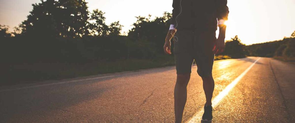 A person walking on the middle of the street in athletic wear. 