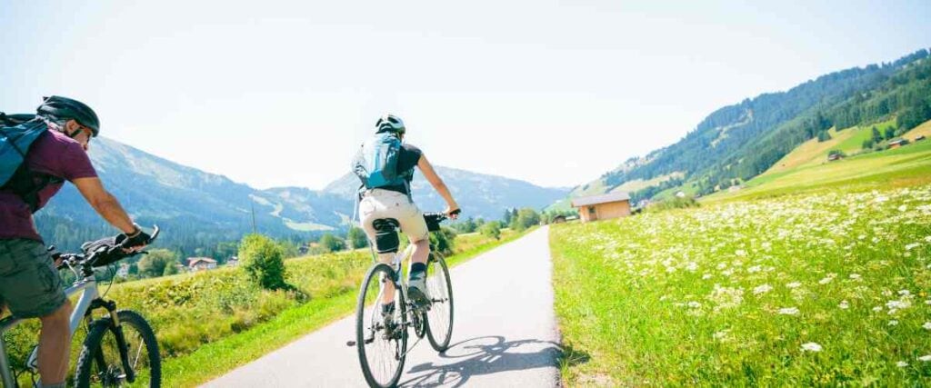 A couple on a bike path with loads of wild flowers.
