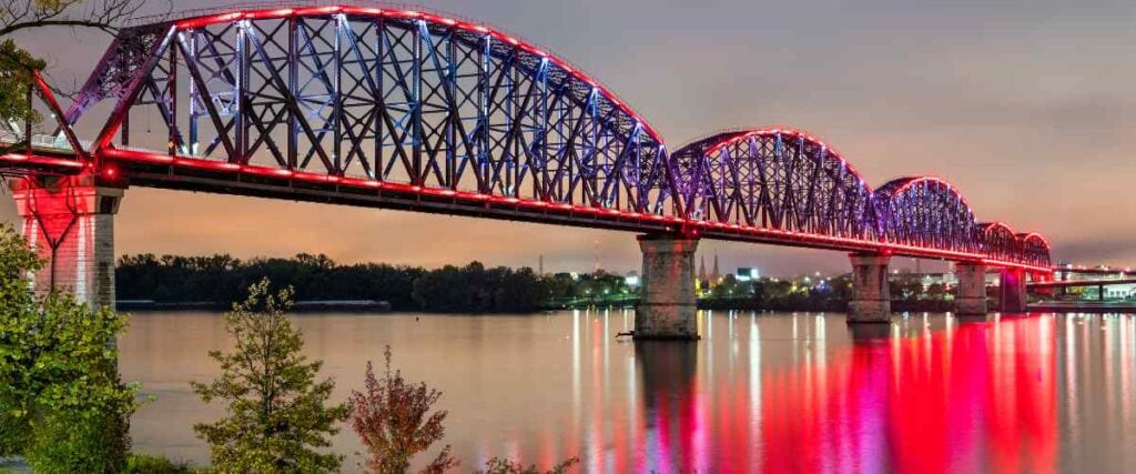 The Big Four Bridge at night light up reflecting on the river. 