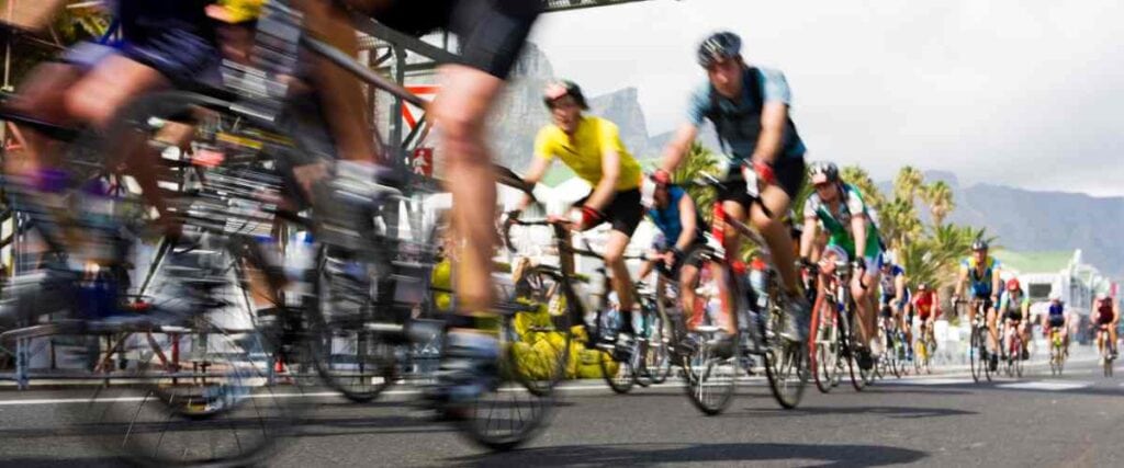 Group of cyclists riding competitively under a bridge.