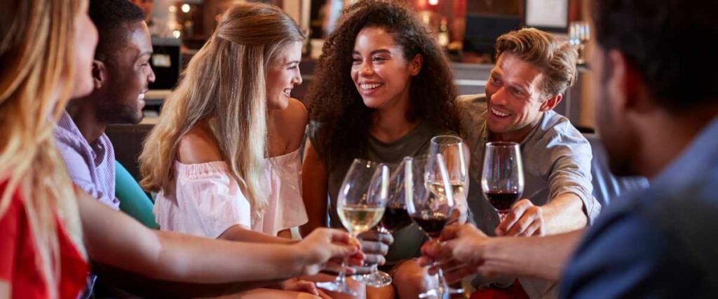 A group of people at a bar smiling at each other.