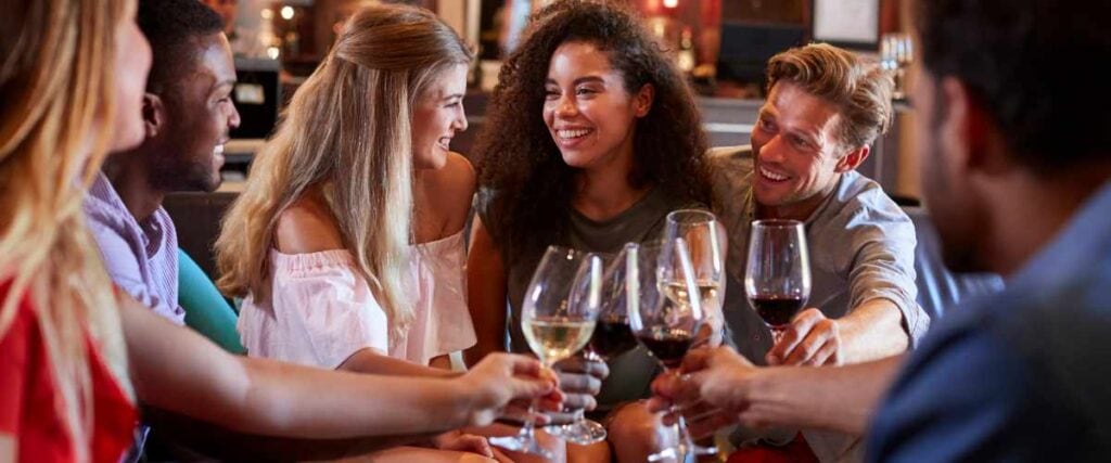 A group of people at a bar smiling at each other. 