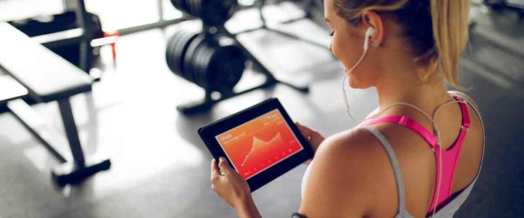 A woman at gym looking at her tablet and her exercise progress throughout the year.