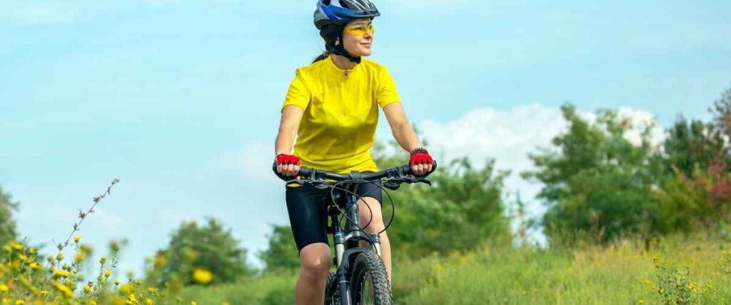 A female cyclists on the Landon Nature Trail in the summer time with bright blue skies behind her. 