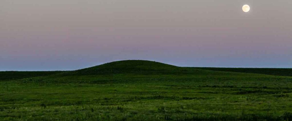 Flint Hills as dusk with the moon shining over the field. 