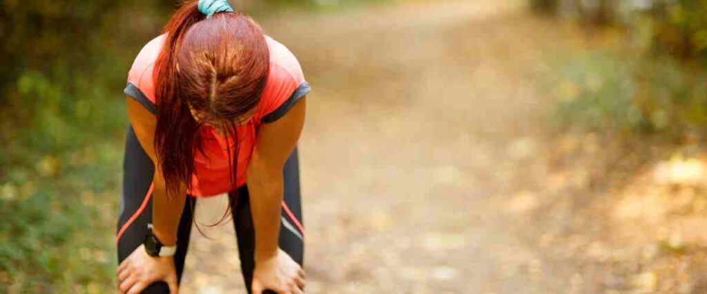 A female runner bent over tired. 